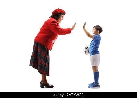 Photo pleine longueur d'un joueur de football de garçon gestuant haut cinq avec une femme âgée isolée sur fond blanc Banque D'Images