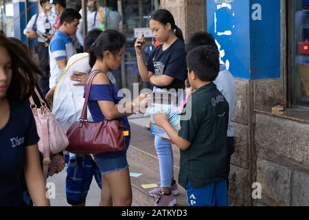 Enfants vendant des masques de protection sur une rue latérale à Cebu City, Philippines.Avec la première mort de Coronavirus enregistrée récemment dans le pays plus de gens prennent des précautions pour prévenir l'infection. Banque D'Images