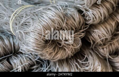 Nouilles de riz brutes. Elles sont grises et sèches, fraîches et saines. Sur le marché ressemble à des threads.Ils sont sur un écran à vendre. Fait à la main. Banque D'Images
