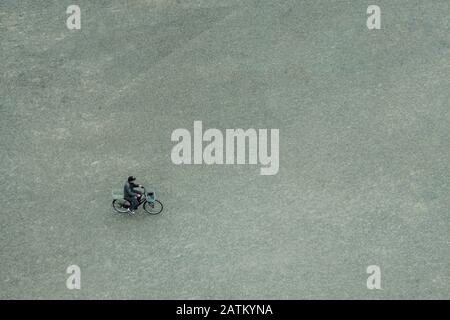 Un seul homme est à vélo. Asphalte gris. Il rentre à la maison du travail. Banque D'Images