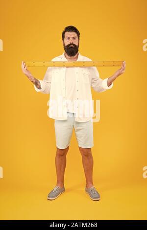 Moustachu et barbu. Homme barbu barbe de mesure sèche sur fond jaune. Professeur de mathématiques de barbus ou étudiant avec règle métrique. Guy caucasienne brutale d'être fiers de la croissance des cheveux sur le visage barbu. Banque D'Images