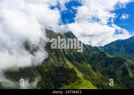 Vue d'en haut, vue imprenable aérienne d'une chaîne de montagnes verdoyante entourée de nuages et d'un beau ciel bleu en arrière-plan. Sembalun, Lombok. Banque D'Images