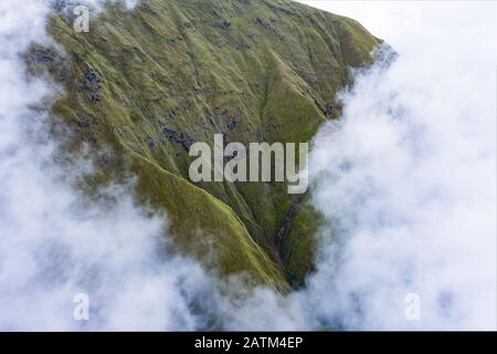 Vue d'en haut, vue imprenable aérienne d'une chaîne de montagnes verdoyante encadrée par des nuages. Sembalun, Lombok, Nusa Tenggara Ouest, Indonésie. Banque D'Images