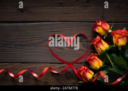 Roses jaunes rouges et coeur en forme de ruban sur fond de bois. Saint Valentin, Fête Des Mères, Joyeux Anniversaire, Mariage, Fête Des Femmes - Concept Banque D'Images