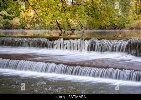 Eau en cascade au-dessus d'un barrage de dérivation sur la rivière Poudre avec des couleurs d'automne en arrière-plan, nature et concept industriel Banque D'Images