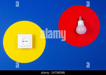 Ampoule lampe et de l'énergie électrique et les prises rouge et jaune géométriques sur fond bleu marine Banque D'Images