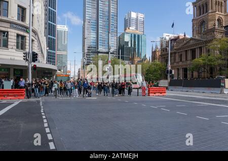 Sydney, Australie - 20 septembre 2019 : piétons attendant de traverser la rue dans le quartier central des affaires de Sydney avec un tramway sur la rue George Banque D'Images