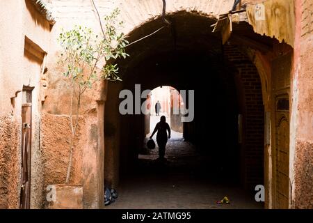 Une figure silhouettée marche le long d'une allée dans la médina de Marrakech, Maroc Banque D'Images