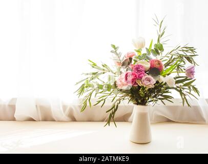 Magnifique bouquet de fleurs délicates avec roses, eustomes et feuilles d'eucalyptus dans un vase sur un seuil de vent Banque D'Images