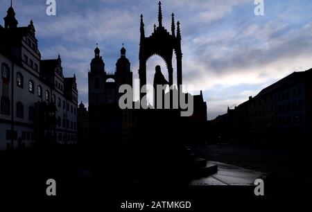 04 février 2020, Saxe-Anhalt, Wittenberg: Les tours jumelles de l'église de la ville de Sainte Marie et le monument de Philipp Melanchthon se démarquent comme silhouettes sur la place du marché à Wittenberg. Aujourd'hui (04.02.2020) la Cour Régionale Supérieure de Naumburg devrait annoncer une décision sur la suppression d'un soulagement anti-juif du mur de l'église. Un homme a intenté un procès contre l'église protestante parce qu'il se sent insulté par la sculpture diffamatoire. Il exige que le relief de grès connu sous le nom de Judensau soit retiré de la façade de l'église de la ville. Le demandeur est membre d'une commu juive Banque D'Images