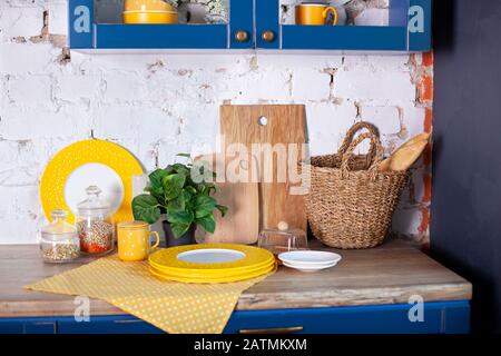 Ustensiles de cuisine, décoration maison cuisine. Intérieur de la cuisine avec planches à découper et assiettes sur la table contre le mur de briques blanches. intérieur de la salle à manger. Banque D'Images