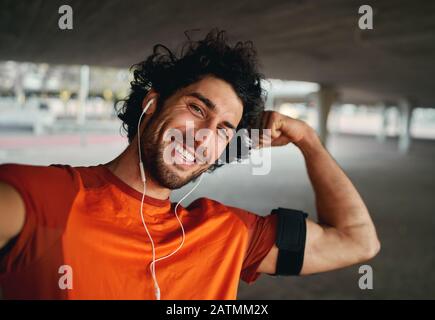 Un sportif souriant et confiant qui prend un selfie et fléchit les muscles tout en regardant dans l'appareil photo Banque D'Images