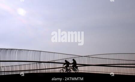 Silhouette de deux personnes en vélo pliable sur le pont contre le ciel bleu Izmir, Turquie. Banque D'Images