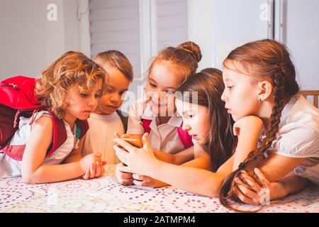 Groupe d'enfants d'école avec smartphone s'amuser en cours de pause en classe Banque D'Images