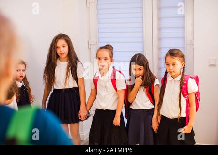 Groupe de écolières tenant les mains pendant la pause dans le couloir. Intimidation scolaire Banque D'Images