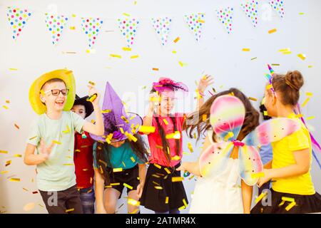 Joyeux enfant à danser à la fête d'anniversaire. Les enfants profitent de confettis pailletés Banque D'Images