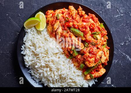 les fajitas de dinde maison sont cuits avec des légumes et de la sauce tomate servis avec du riz long grain à la vapeur et des tranches de citron vert sur une assiette, vue horizontale d'un Banque D'Images