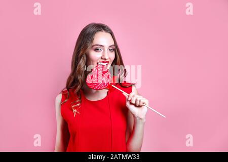 Mode douce femme s'amuser avec la lollipop sur fond rose Banque D'Images