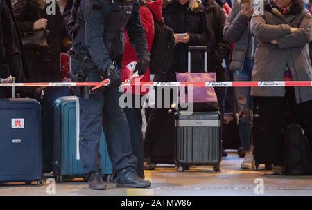 Stuttgart, Allemagne. 04 février 2020. Un policier ferme un tunnel dans la gare principale avec un ruban adhésif, derrière lequel attendent les passagers avec des valises. La gare centrale de Stuttgart a été fermée mardi matin à cause d'une opération de pompiers. Le service ferroviaire a été complètement arrêté, a déclaré un porte-parole de la police fédérale. Crédit: Marijan Murat/Dpa/Alay Live News Banque D'Images