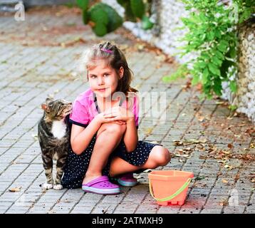 Le chat regarde dans le visage de la fille assise sur la rue . Yalta. Crimée. Banque D'Images