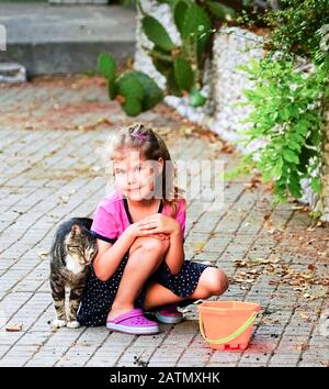 Le chat frotte la main de la fille sur la rue . Yalta. Crimée. Banque D'Images