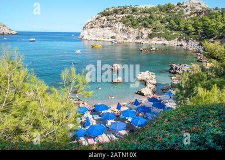 Petite plage avec touristes, parasols et chaises longues dans la baie Anthony Quinn (Rhodes, Grèce) Banque D'Images