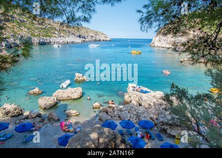 Petite plage avec touristes, parasols et chaises longues dans la baie Anthony Quinn (Rhodes, Grèce) Banque D'Images