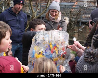 Les enfants hack déterminé à une sculpture sur glace contenant des bonbons et chocolats qu'ils peuvent manger s'ils les libèrent à York Ice Trail 2020 Banque D'Images