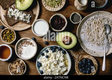 Petit déjeuner sain. Assortiment de plats de petit déjeuner composé de blé, yaourt, kéfir, fromage cottage, avocat, pain de seigle, graines, noix et baies i Banque D'Images