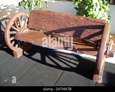 Tir cropé d'un banc en bois avec roues de wagon à l'extérieur d'une structure Banque D'Images