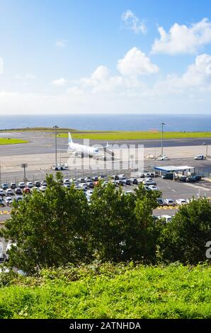 Ponta Delgada, Açores, Portugal - 14 Janvier 2020: Vue De L'Aéroport Joao Paulo Ii Sur L'Île De Sao Miguel. Piste avec un avion, la construction du terminal et le parking pour les voitures de location. Océan en arrière-plan. Banque D'Images