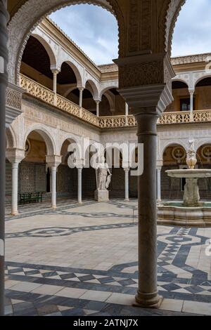 Les arches ornées de poignées de paniers des palais historiques d'été et d'hiver entourant le patio principal dans la casa de Pilatos (Pilate's House). Banque D'Images