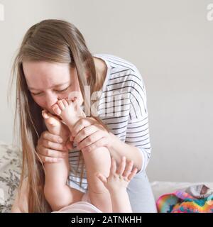 La jeune mère embrasse les talons des enfants, routine du matin Banque D'Images