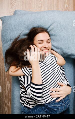 Concept de la fête des mères, jeune femme heureuse brunette embrassant son petit enfant et souriant avec des yeux fermés, moment tendre à la maison, vue de dessus Banque D'Images