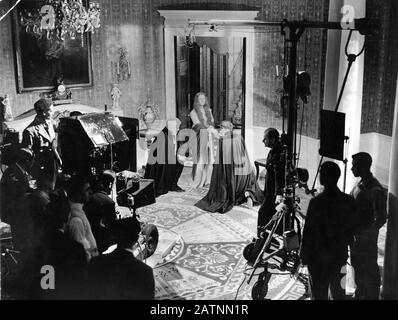 ANNA NEAGLE dans le rôle de la Reine Victoria sur le plateau franc avec le réalisateur HERBERT WILCOX (debout à côté de la perche du microphone) et l'équipe de tournage de VICTORIA THE GREAT 1937 Herbert Wilcox Productions / RKO radio Pictures Banque D'Images