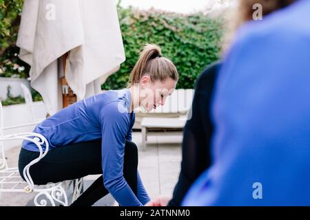 Deux jeunes sportives lier ses lacets avant la formation sur une terrasse port sweatshirt. Banque D'Images