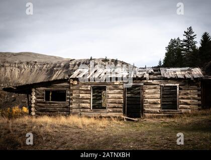 Un relict des premiers pionniers : l'ancien bâtiment rustique de la ferme Potwell devant les célèbres huoodoos et dunes de sable de Farwell Canyon, en Colombie-Britannique. Banque D'Images