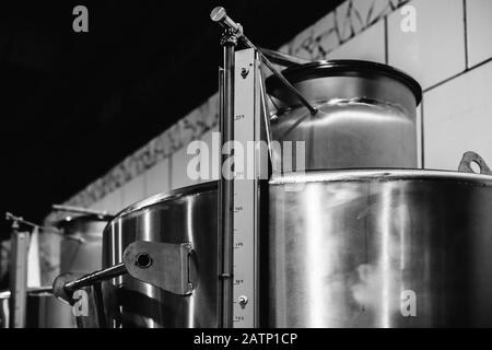 Fûts en acier inoxydable dans une rangée, équipement d'usine de vin. Photo en noir et blanc Banque D'Images