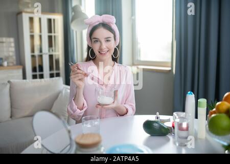 Une jolie fille souriante dans un bandeau rose tenant un bol dans ses mains Banque D'Images
