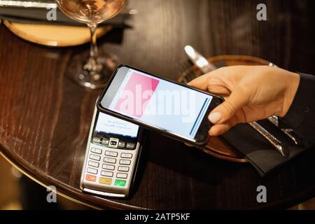 Personne non reconnaissable utilisant un téléphone mobile pour payer un repas. Banque D'Images