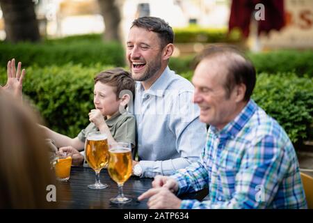 Une famille de plusieurs générations qui a un verre ensemble à l'extérieur dans un bar. Banque D'Images
