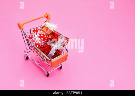 Panier rempli de cadeaux de Noël sur fond rose. Banque D'Images
