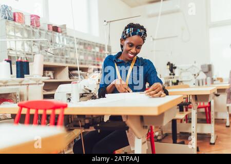 Jeune ouvrier africain du textile à coudre sur la chaîne de production. Femme couturière travaillant avec machine à coudre Banque D'Images