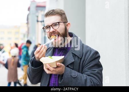 Concept de nourriture, de nourriture et de style de vie - jeune homme avec repas mange dans la rue de la ville Banque D'Images