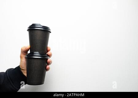 La main du Mans contient deux tasses de café en papier noir Banque D'Images