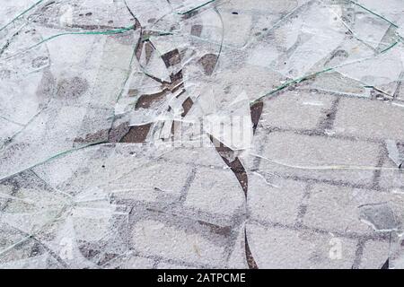 Des éclats de verre brisé se rapprocheent sur le trottoir Banque D'Images