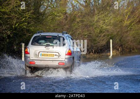 La photo du 27 janvier montre un véhicule roulant sur l'A1101 partiellement inondé à la frontière Cambridgeshire/Norfolk. L'eau inondée le long d'un tronçon de route notoire à Welney, à la frontière Cambridgeshire/Norfolk, a disparu, révélant aujourd'hui QUATRE voitures tordées incroyables (LUN). Les automobilistes ont tous été pris par le long et sinueux tronçon de route, qui a été inondé pendant deux mois. Quatre personnes ont dû être sauvées de l'une des voitures par des pompiers après qu'il a été pris à Welney Wash le 18 janvier. Les voitures abandonnées, qui ont toutes été victimes de la route inondée, seront en mesure d'être Banque D'Images