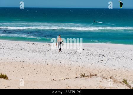 Le surfeur descend le long du sable à la célèbre plage de surf de cerf-volant à Haakgat point, Otto due Plessis Drive, Melkbosstrand, Capte Town, Afrique du Sud Banque D'Images