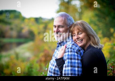 Un couple d'âge mûr qui profite de temps ensemble et de coucher de soleil le long d'une rivière dans un parc municipal lors d'une chaude soirée d'automne; St. Albert, Alberta, Canada Banque D'Images