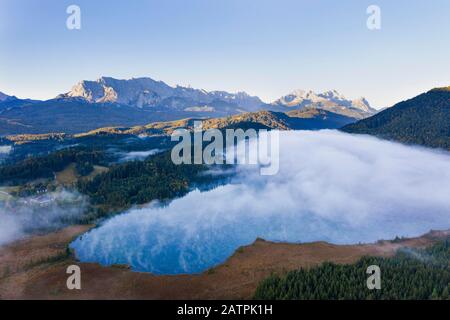 Gaufre de brouillard sur le lac de Barmsee près de Kruen, plage de Wetterstein avec Wettersteinwand et Zugspitze, Werdenfelser Land, drone shot, Haute-Bavière Banque D'Images